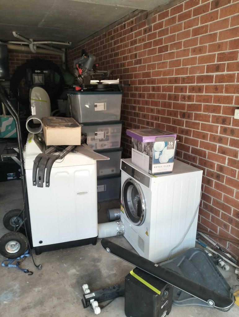 garage in dulwich hill with washing machine dryer appliances and boxes of items moments before otg completes a garage clean up
