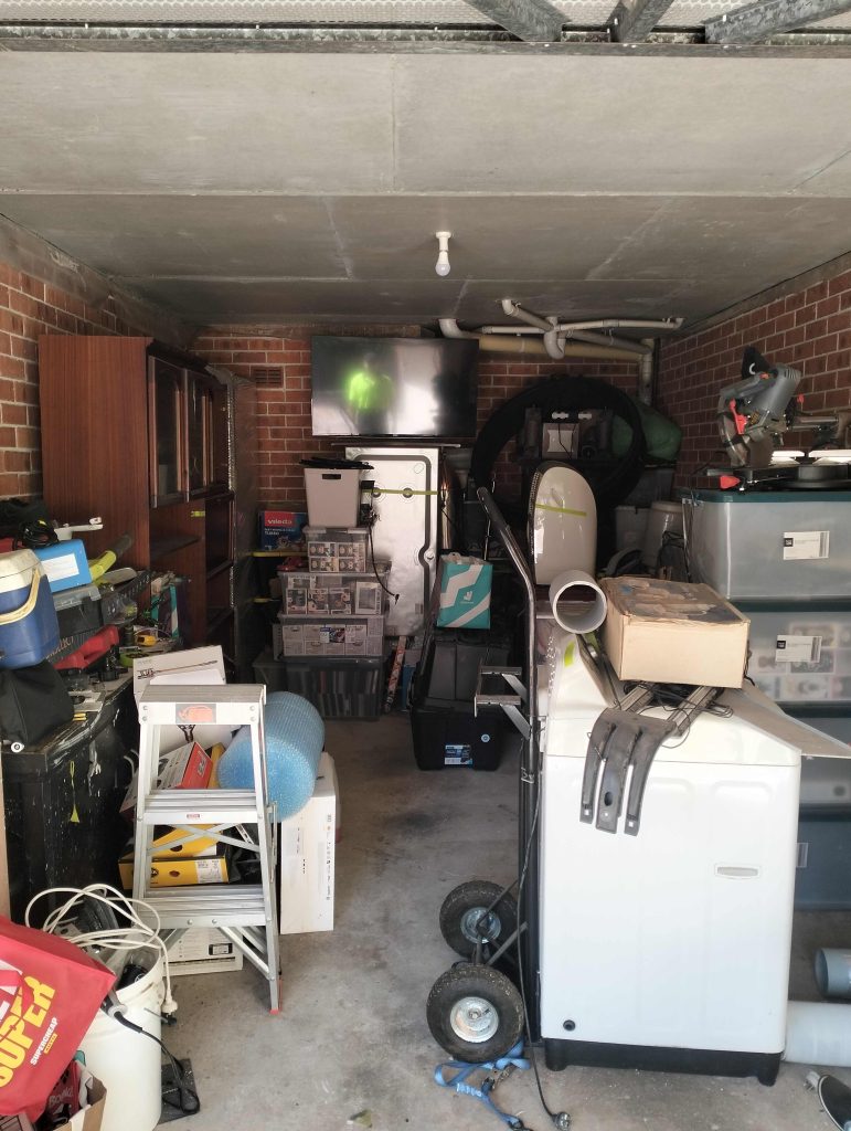 picture of garage in dulwich hill with appliances tv cupboards washing machine .Its almost a full garage .Before a otg rubbish garage clean up